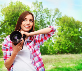 Young female photographer taking photos on nature background