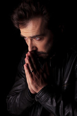 young man holding his hands together praying.