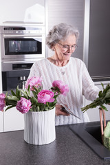 aktive Seniorin stellt Blumen in die Vase