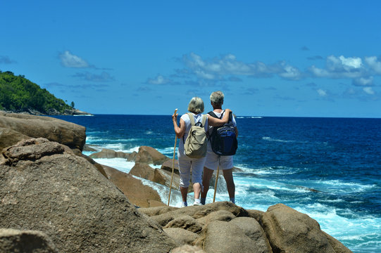 elderly couple standing back on the beach