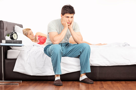 Worried man sitting on bed and a girl sleeping