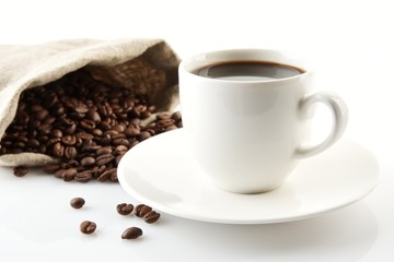 Cup of coffee with saucer with bag with coffee beans on white