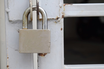 Old padlock hanging on gray metal door