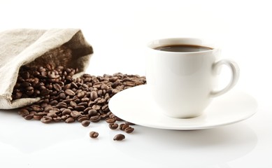 Cup of coffee with saucer with bag with coffee beans on white