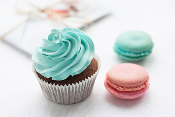 Сolorful macaroons with cupcake and present on the background