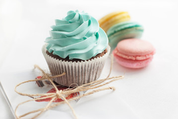 Сolorful macaroons with cupcake and present on the background