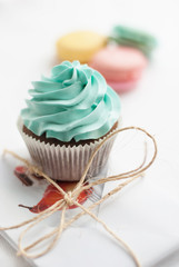 Сolorful macaroons with cupcake and present on the background