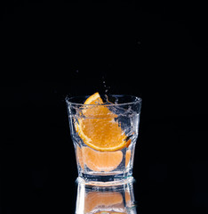 Slice of lemon splashing into a glass of water with a spray of water droplets 