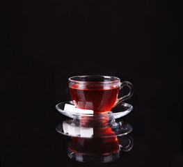 Glass cup of tea on black background.