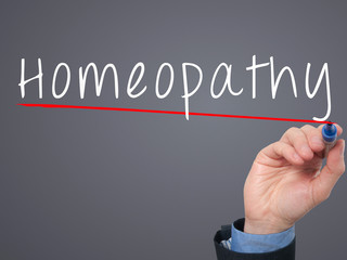 Man Hand writing Homeopathy with marker.