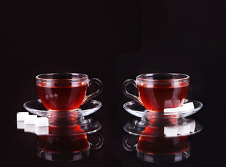 Glass cup of tea on black background.