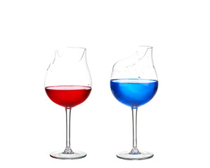 Two broken glasses with red and blue cocktail on white isolate