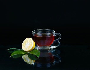 Glass cup of tea on black background.