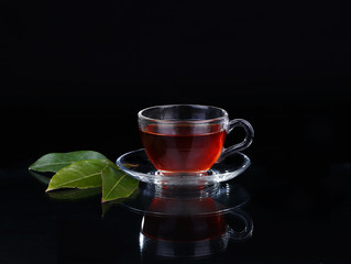 Glass cup of tea on black background.