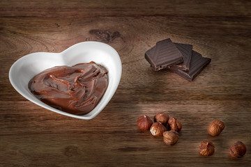 chocolate cream, hazelnut and chocolate on wooden table