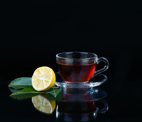 Glass cup of tea on black background.