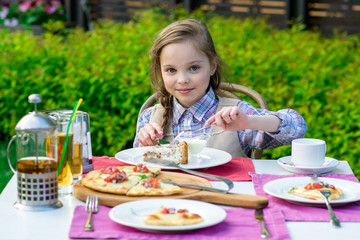 cute little girl sitting by dinner table and eating