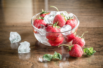 Fresh strawberries with ice cubes in the glass bowl