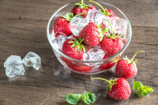 Fresh strawberries with ice cubes in the glass bowl