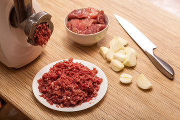 The electric meat grinder, forcemeat, onions and the cut meat