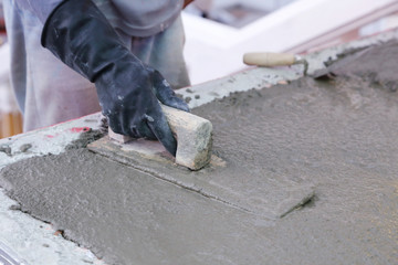 hand using trowel to finish wet concrete