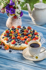 Fruit tart served with coffee in the summer garden