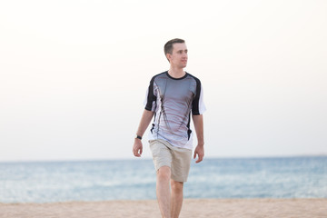 Fototapeta na wymiar Young man walking on the beach