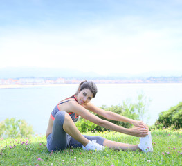 Naklejka na ściany i meble Young fitness woman doing stretching exercises outside