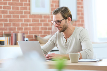 Blond guy sitting in front of laptop computer at home