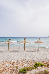 Straw umbrellas on sand beach.