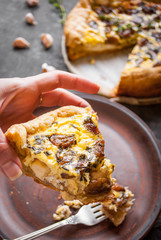 Woman's hand holding a caramelized garlic tart with goat cheese