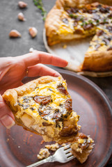 Woman's hand holding a caramelized garlic tart with goat cheese