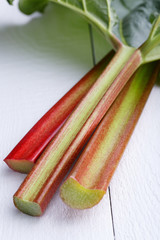 Bundle of rhubarb on white wooden table.