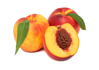 Two whole and a half nectarine with green leaves (isolated)