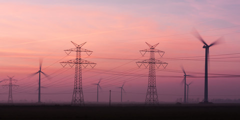 Strommasten und Windräder in der Abenddämmerung