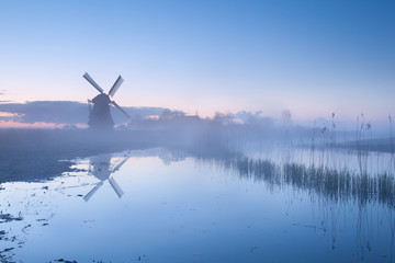 Fototapeta na wymiar Dutch windmill in dense sunrise mist