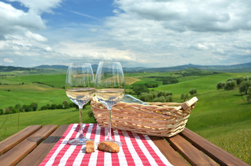 Two wineglasses and cantuccini on the wooden table Tuscan landsc