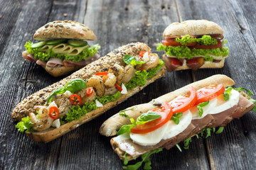 Mixed sandwiches with crispy baguette on a wooden background 