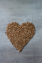buckwheats grains formed in heart shape on wooden background