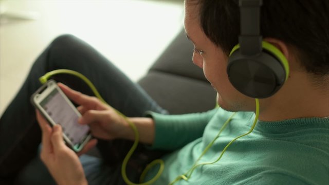 Asian Man Listening Music Podcast On Phone With Earphones