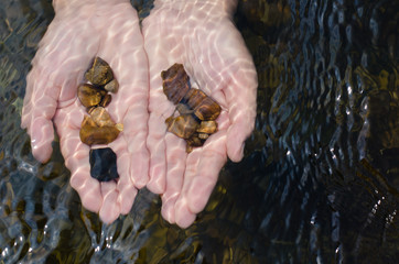 Stones In Hands Under Clear Water.