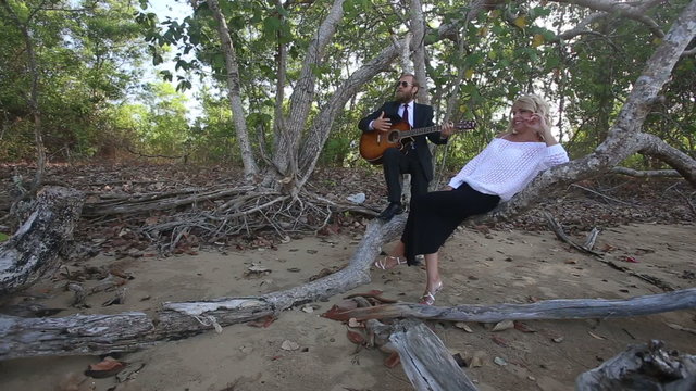 guitarist plays for girl she smiles and laughs at tropical tree