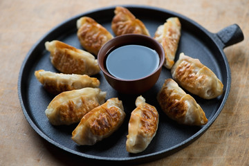 Frying pan with gyoza dumplings and a dipping sauce, close-up