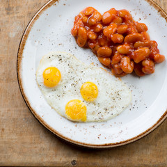Breakfast with fried quail eggs and beans, close-up, top view