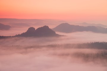 Fototapeta na wymiar Fogy red daybreak. Misty beautiful hills and peaks in Sun rays