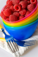 red raspberry in colorfull bowls with fork