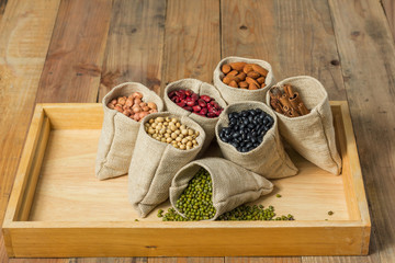 Different kinds of beans and cinnamon in sacks bag on wooden background