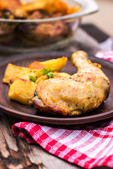 Baked chicken pieces with potatoes, herbs and garlic
