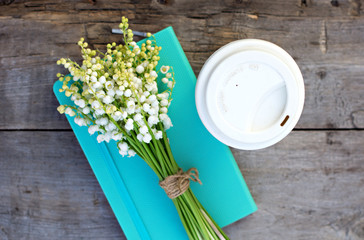 diary, a glass of coffee and  lilies of valley  on the table