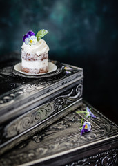 Little cake decorated with fresh viola flower. 